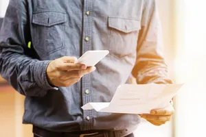 particulier tient téléphone et facure